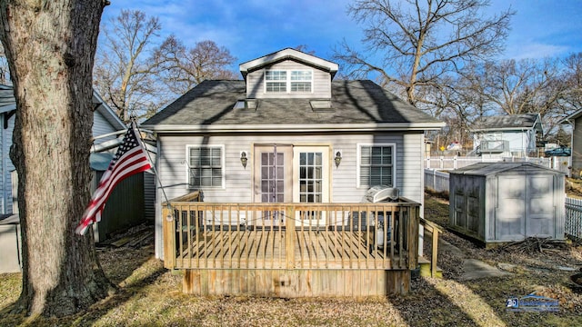 rear view of property with a storage unit, an outbuilding, a deck, and fence