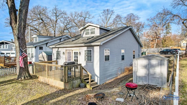 back of property featuring a deck, a storage shed, fence, and an outdoor structure