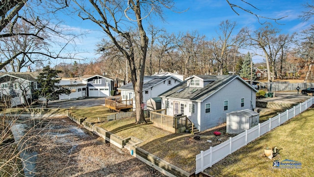 exterior space with a vegetable garden, a fenced backyard, a front lawn, an outdoor structure, and a residential view