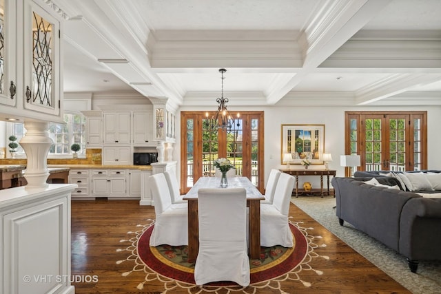 dining room with dark wood-type flooring, ornamental molding, a chandelier, and french doors