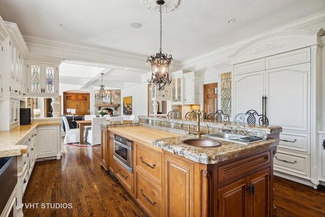 kitchen with decorative light fixtures, dark wood-type flooring, an island with sink, and white cabinets