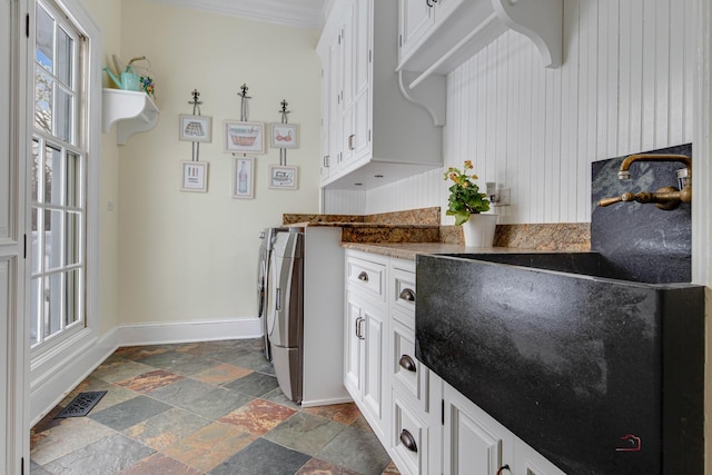 kitchen with white cabinetry, sink, crown molding, and washer and dryer