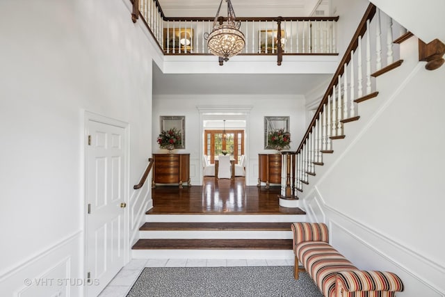 foyer entrance with ornamental molding, a high ceiling, and a notable chandelier