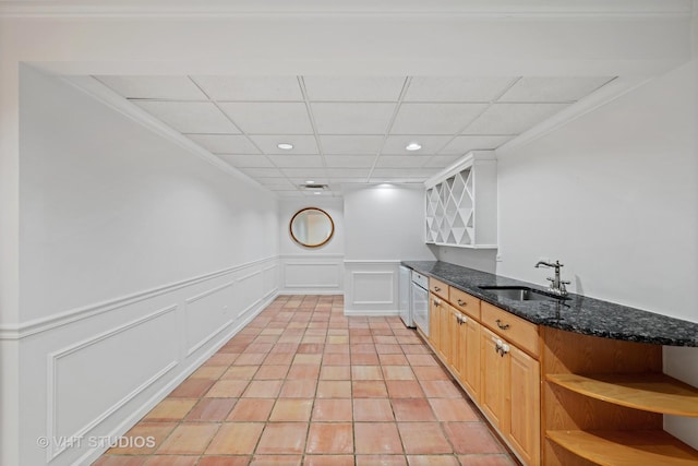 kitchen featuring light tile patterned flooring, a paneled ceiling, light brown cabinetry, sink, and dark stone counters