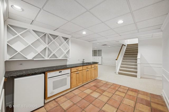 kitchen featuring light brown cabinetry, sink, oven, and a drop ceiling