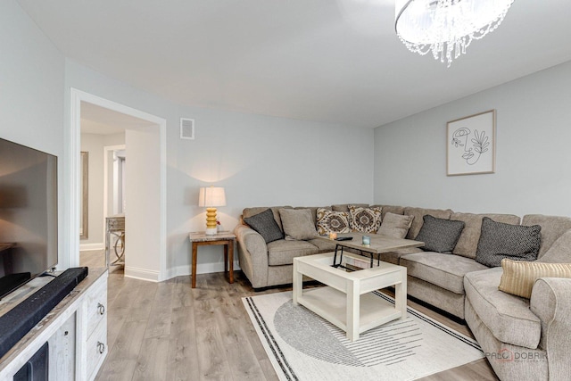 living room featuring a chandelier and light wood-type flooring