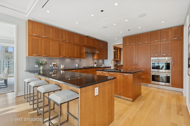 kitchen featuring sink, appliances with stainless steel finishes, a kitchen breakfast bar, kitchen peninsula, and range hood