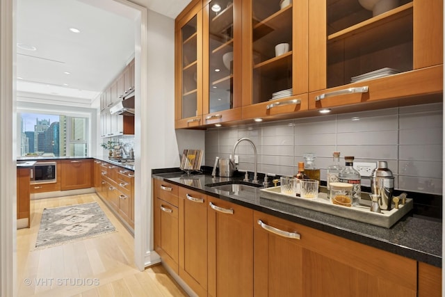 kitchen featuring tasteful backsplash, black microwave, sink, and dark stone counters