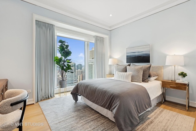 bedroom featuring ornamental molding and light hardwood / wood-style flooring