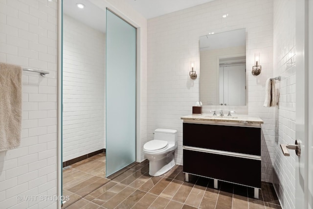 bathroom with tile patterned flooring, vanity, tile walls, and toilet