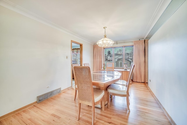 dining area featuring an inviting chandelier, crown molding, and light hardwood / wood-style floors