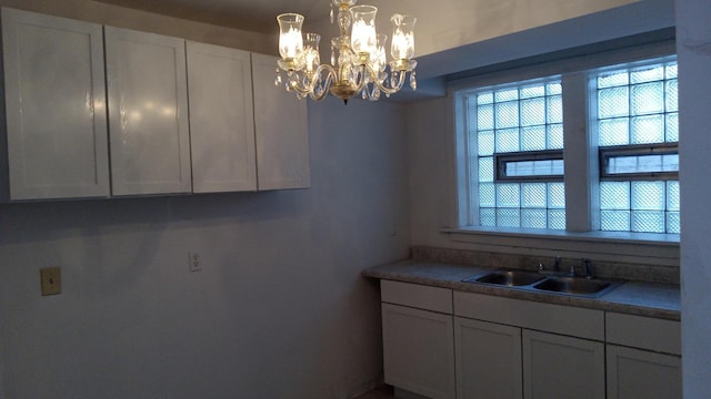 interior space with sink, white cabinets, and a chandelier