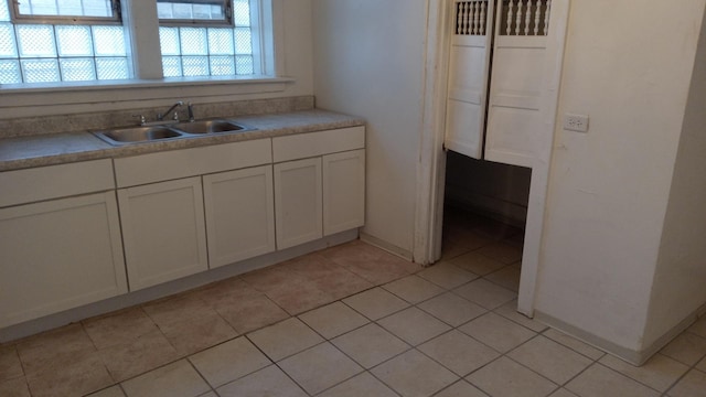 kitchen featuring sink, light tile patterned floors, and white cabinets