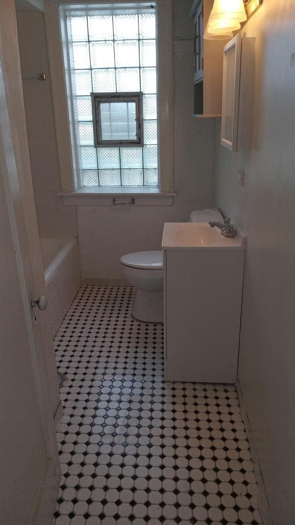 bathroom with vanity, a tub to relax in, tile patterned floors, and toilet