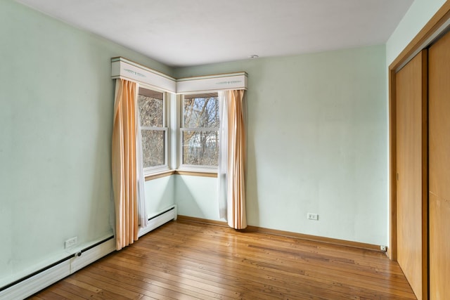 unfurnished bedroom with a baseboard radiator, light hardwood / wood-style floors, and a closet