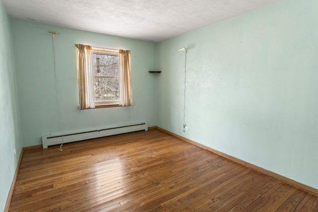 empty room featuring hardwood / wood-style flooring and baseboard heating