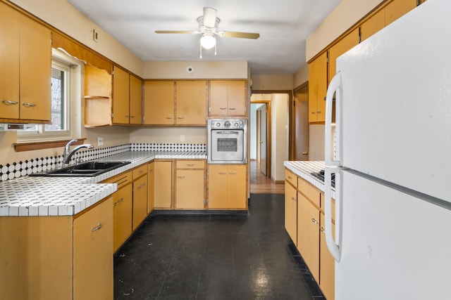 kitchen featuring sink, oven, ceiling fan, and white fridge