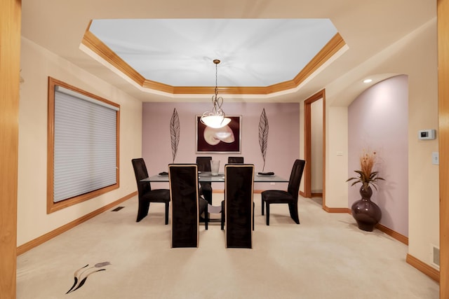 carpeted dining area with crown molding and a tray ceiling