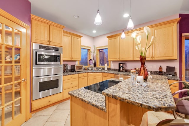 kitchen with hanging light fixtures, light brown cabinets, stainless steel double oven, and a kitchen bar