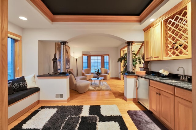 kitchen featuring a raised ceiling, dishwasher, light brown cabinetry, and ornate columns