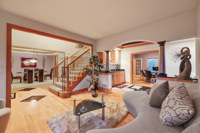 living room with sink, light hardwood / wood-style floors, and ornate columns