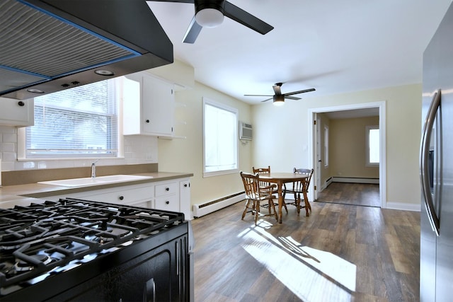 kitchen featuring white cabinets, under cabinet range hood, baseboard heating, and wood finished floors