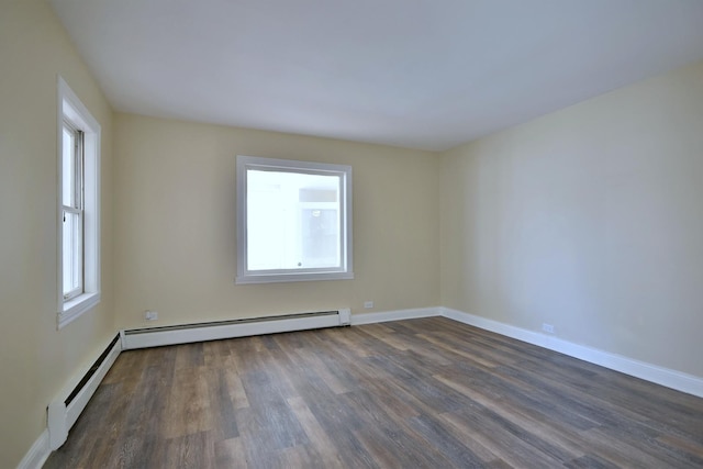 spare room featuring dark wood-style flooring, baseboard heating, and baseboards