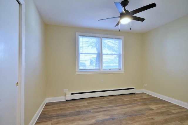 spare room with a baseboard radiator, wood finished floors, a ceiling fan, and baseboards