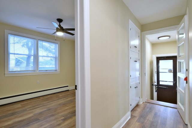 hallway featuring baseboards, baseboard heating, and wood finished floors