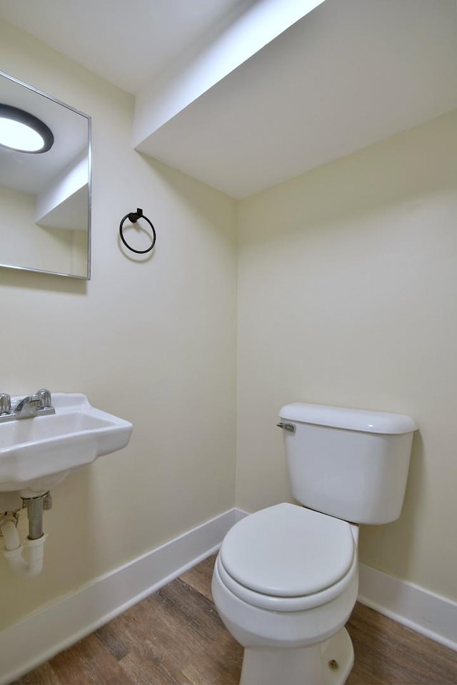 bathroom with toilet, baseboards, and wood finished floors