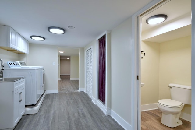 laundry area featuring laundry area, baseboards, washer and clothes dryer, and wood finished floors