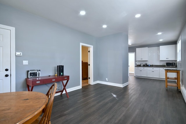 interior space with dark countertops, dark wood-style flooring, stainless steel microwave, and baseboards