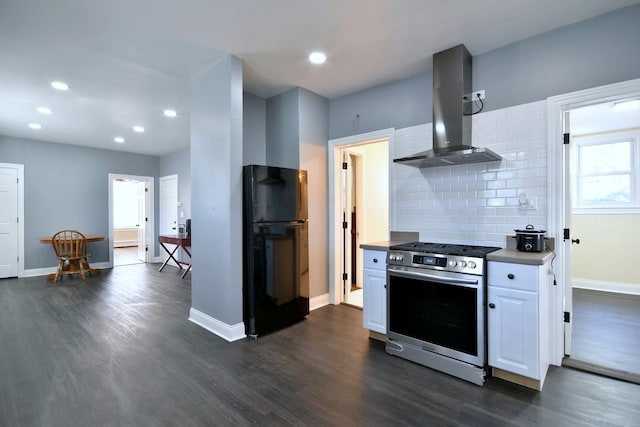 kitchen with dark wood finished floors, decorative backsplash, freestanding refrigerator, ventilation hood, and stainless steel range with gas stovetop