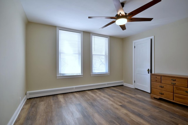 spare room featuring ceiling fan, baseboards, baseboard heating, and dark wood-style flooring