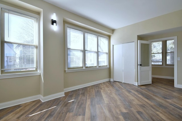 unfurnished bedroom featuring dark wood-type flooring, a closet, and baseboards