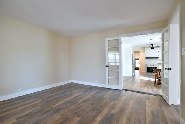 unfurnished room featuring ceiling fan, baseboards, and dark wood finished floors