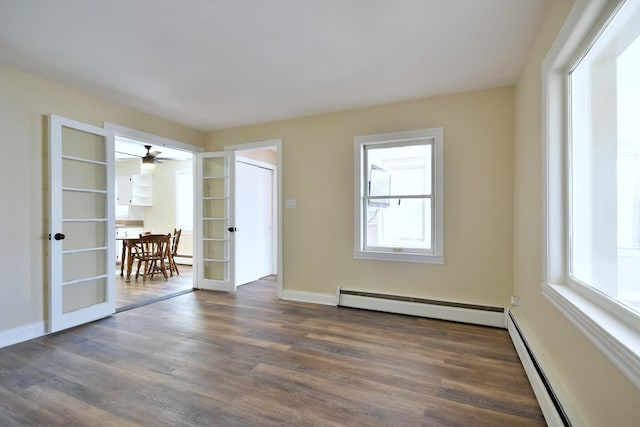 spare room featuring baseboards, a baseboard heating unit, dark wood finished floors, and french doors