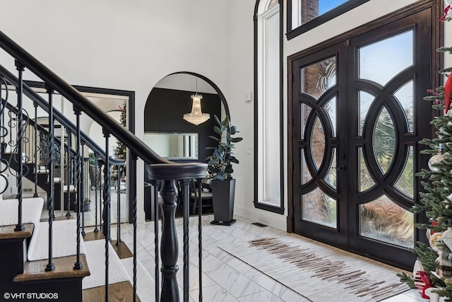 foyer featuring french doors, a towering ceiling, and a wealth of natural light