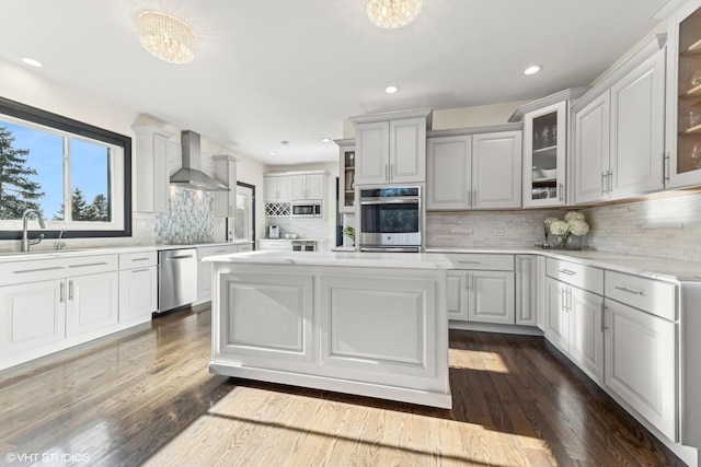 kitchen featuring appliances with stainless steel finishes, dark hardwood / wood-style floors, sink, a center island, and wall chimney exhaust hood