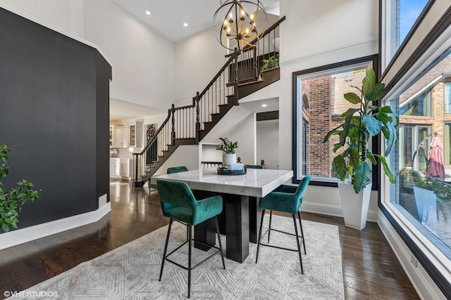 dining space with a notable chandelier, a towering ceiling, and dark wood-type flooring