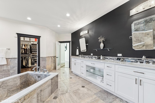 bathroom with a relaxing tiled tub and vanity