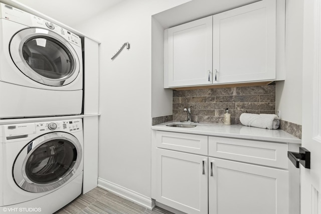 washroom featuring sink, cabinets, and stacked washer / dryer