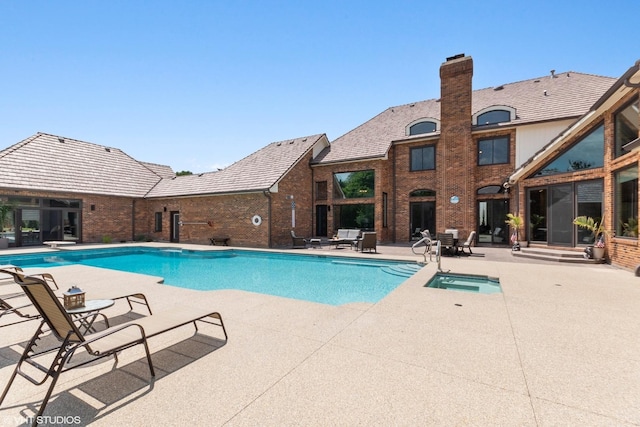 view of pool featuring an in ground hot tub, a diving board, and a patio