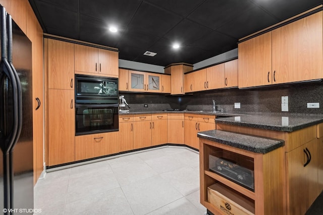 kitchen with sink, decorative backsplash, dark stone counters, and black appliances