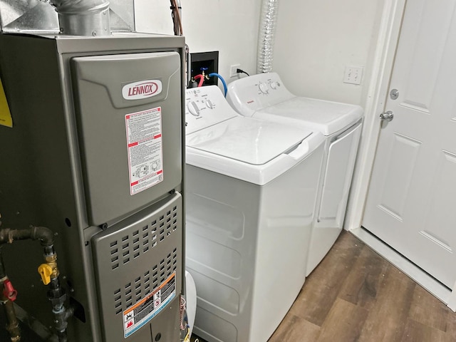 washroom featuring dark hardwood / wood-style floors, washer and clothes dryer, and heating unit