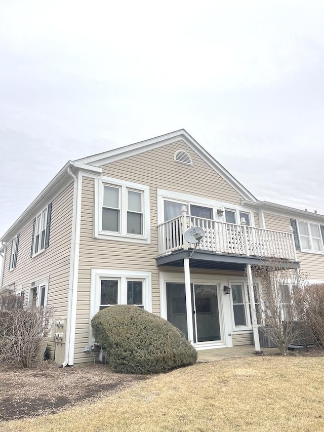 back of property with a balcony and a lawn