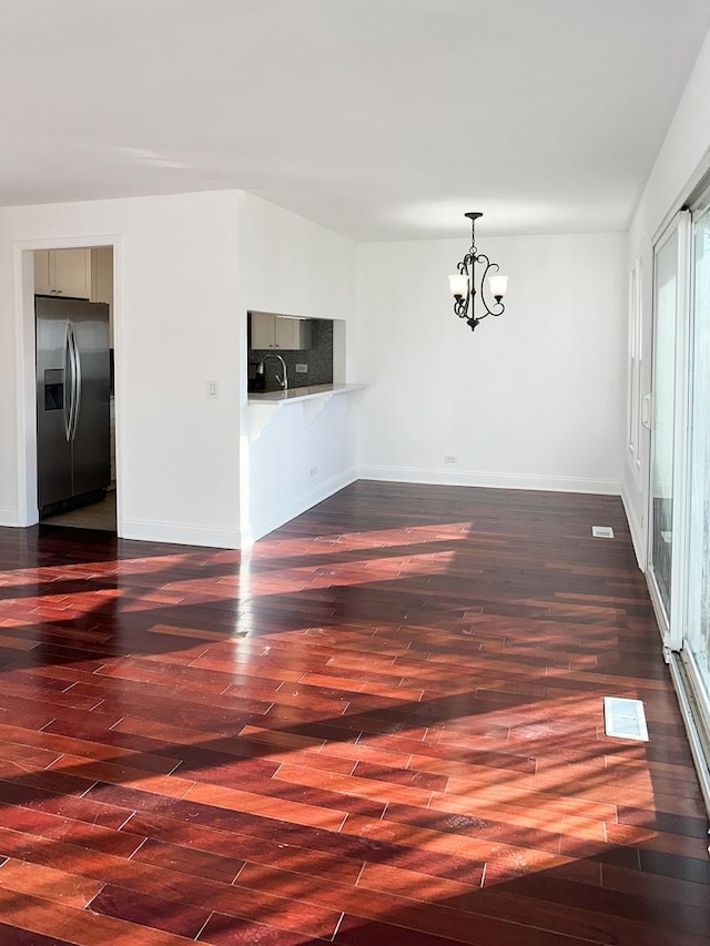 spare room with dark hardwood / wood-style floors and a chandelier