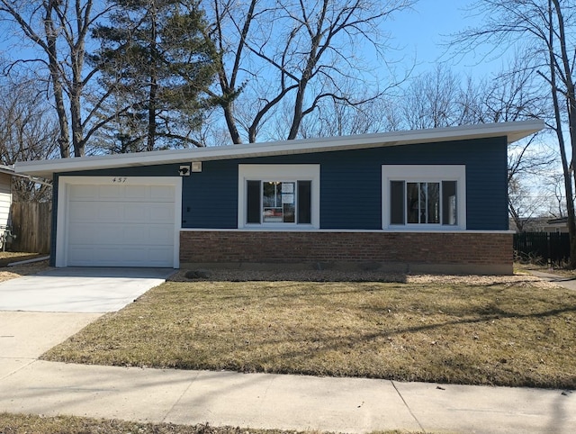 view of front of house with brick siding, a front lawn, fence, a garage, and driveway