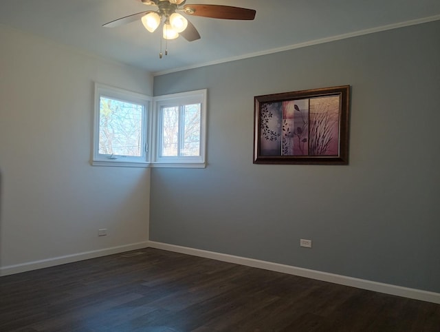 spare room with crown molding, baseboards, dark wood-style flooring, and ceiling fan