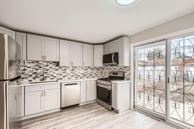 kitchen featuring tasteful backsplash, sink, gray cabinetry, light hardwood / wood-style floors, and stainless steel appliances